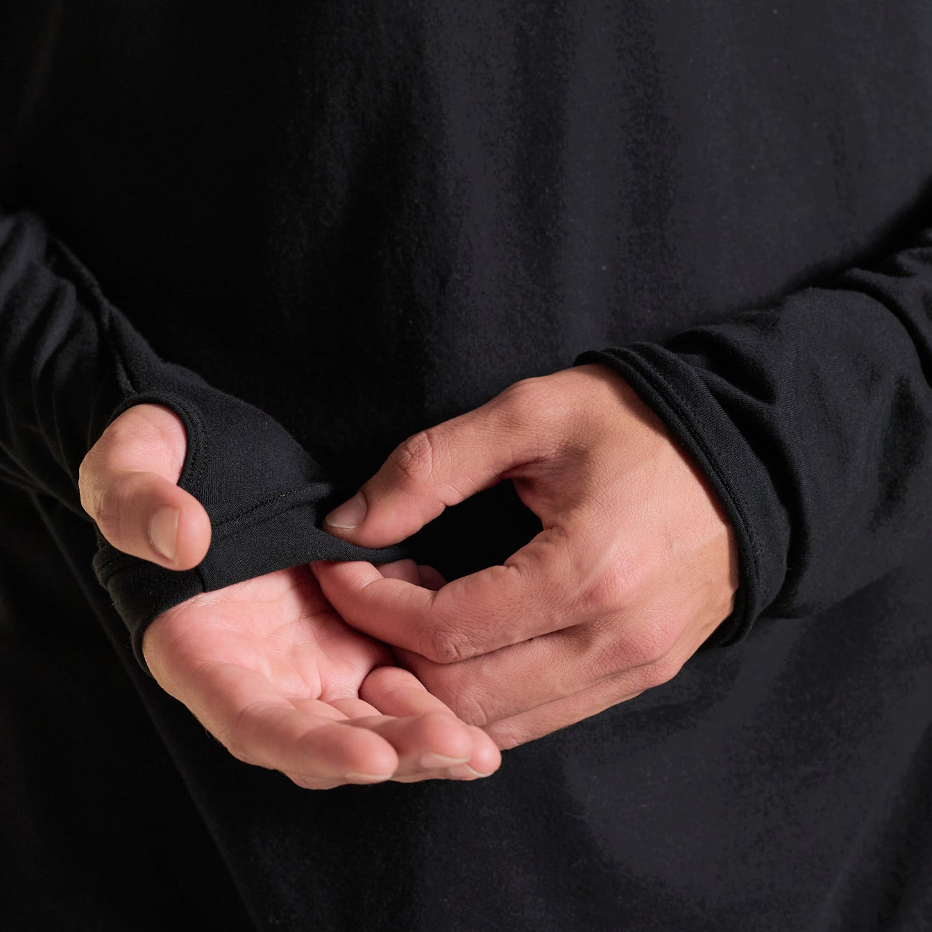 Man modeling black long-sleeve hooded tee